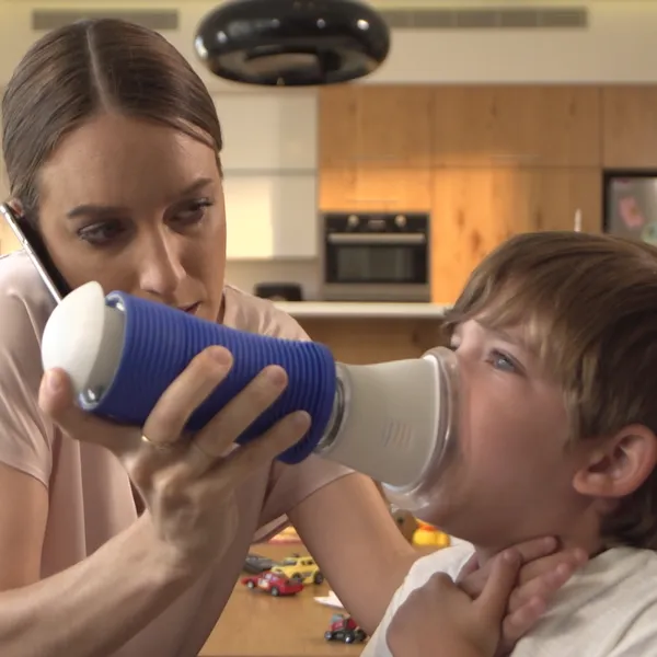 A mother holding a blue Lifewand over her choking son's mouth and nose