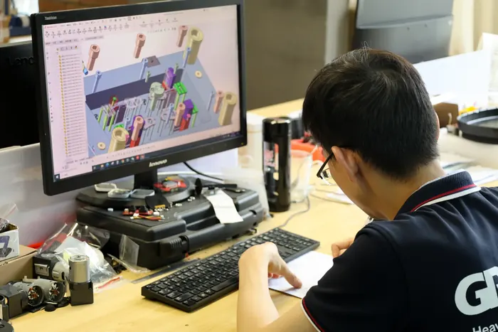 An engineer working in CAD next to a disassembled GRABO